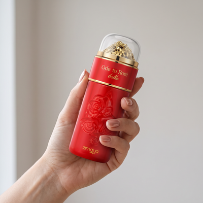 Hand holding Zimaya Ode to Rose Bella perfume, a red bottle with embossed roses and a gold cap