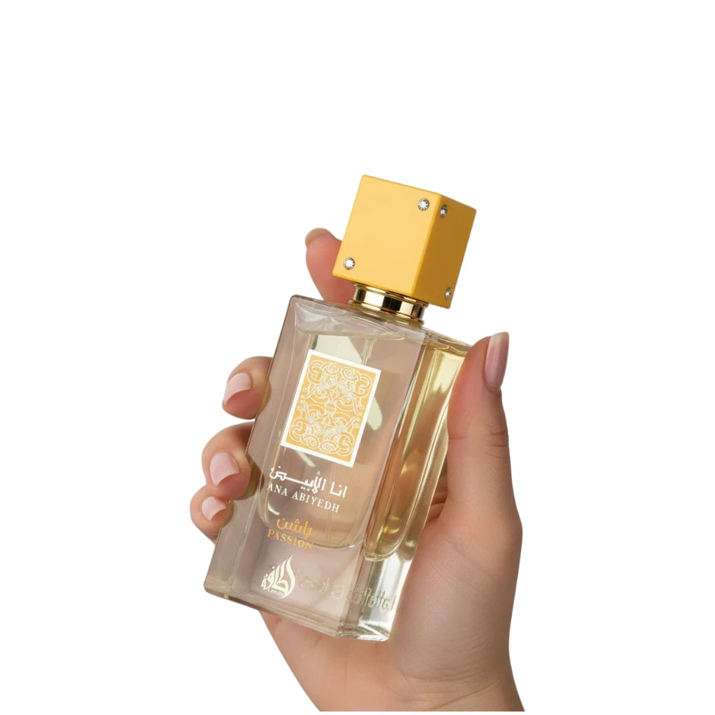 Hand holding a Lattafa Ana abiyedh Passion with a gold cap on a white background