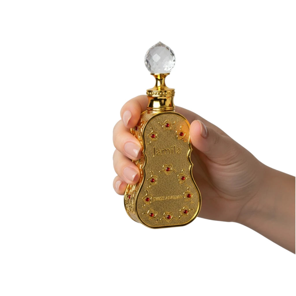 Hand holding a Jamila Perfume Oil bottle with a decorative cap on a white background