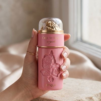 Hand holding Zimaya Ode to Rose Royale women's perfume, a pink bottle with embossed roses and a gold cap