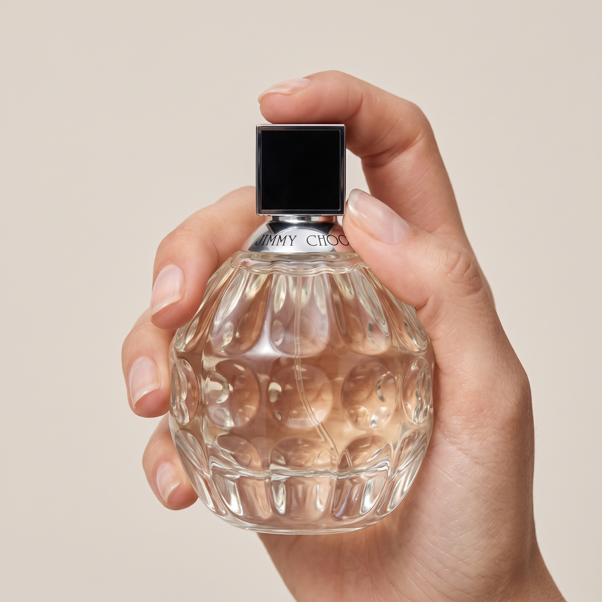 Palette 21 Jimmy Choo Eau de Parfum in a textured glass bottle held by a hand against a neutral background.