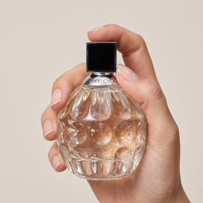 Palette 21 Jimmy Choo Eau de Parfum in a textured glass bottle held by a hand against a neutral background.