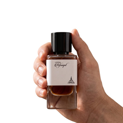 Palette 21 Paris Corner Rifaaqat eau de parfum in a sleek glass bottle held by a hand against a white background.