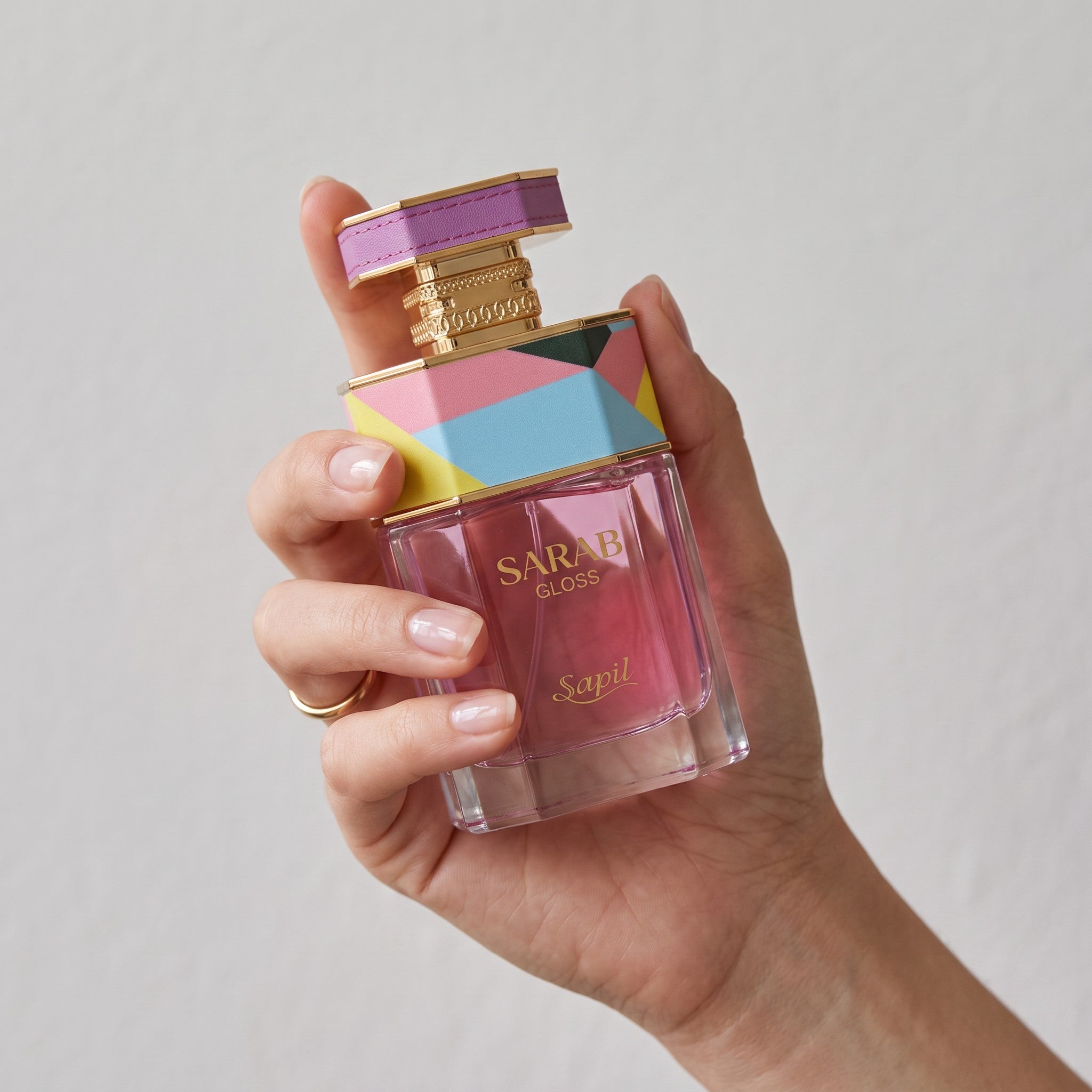 Palette 21 Sarab Gloss Eau de Parfum by Sapil in a geometric bottle with pink liquid held in a woman's hand