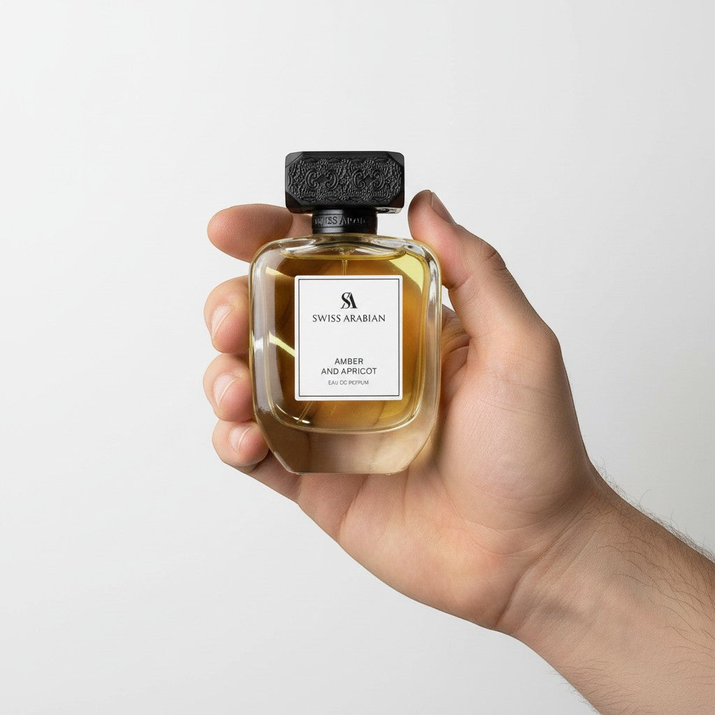 Palette 21 Swiss Arabian Amber and Apricot Eau de Parfum in a glass bottle with a textured black cap held in a hand.