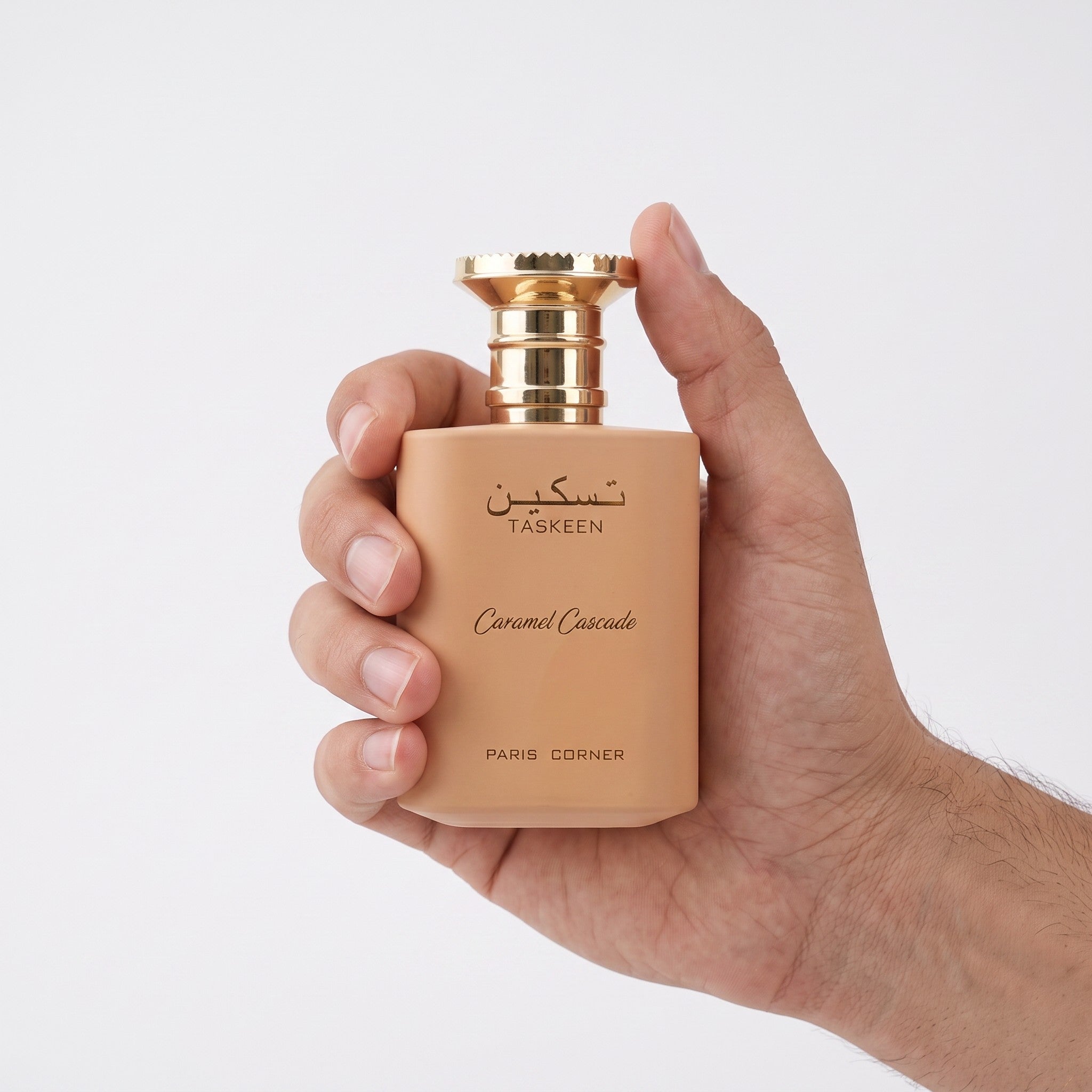 Palette 21 Paris Corner Taskeen Caramel Cascade perfume bottle held in hand, featuring a matte beige finish.